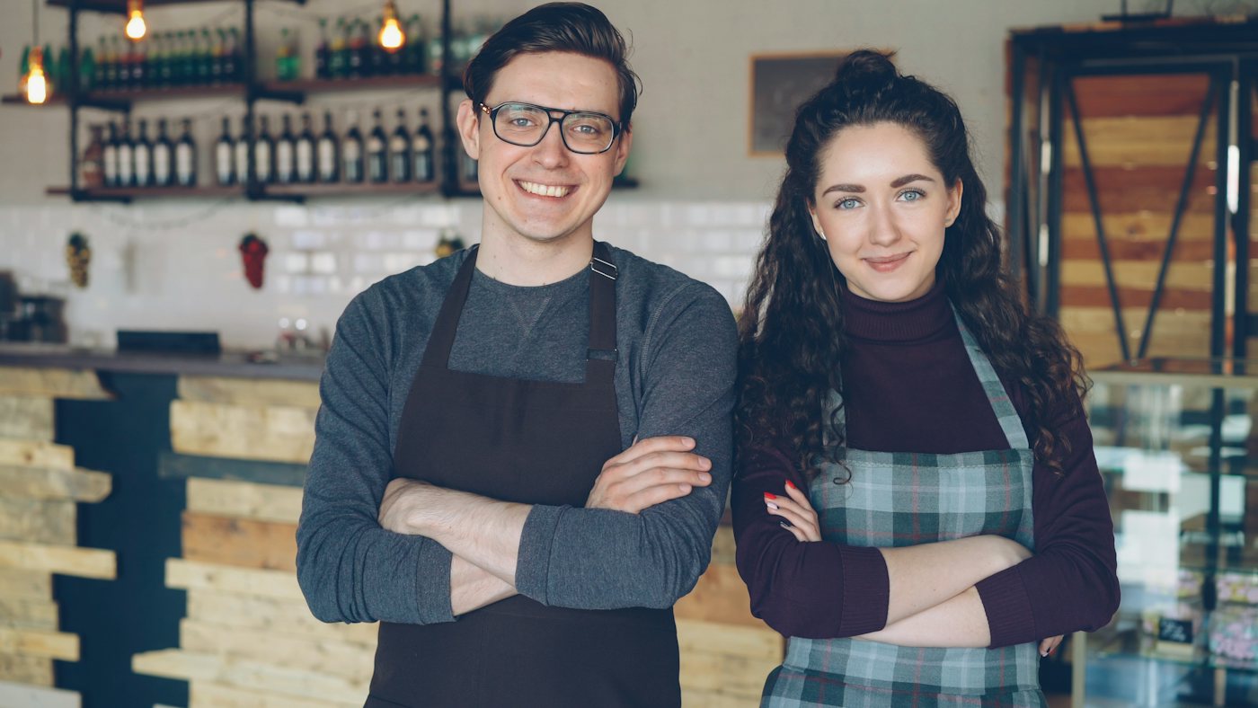 Two small business owners standing together in their cafe