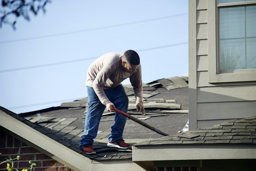 Roofer removing shingles from a house